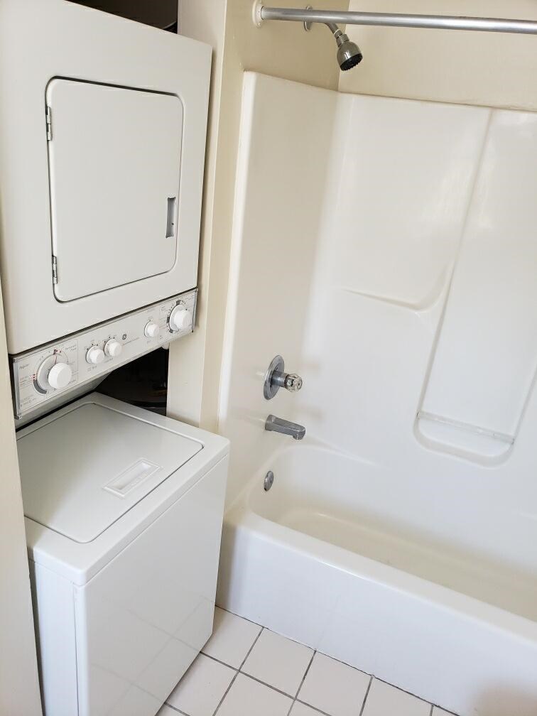 a white bathroom with a washing machine and a tub